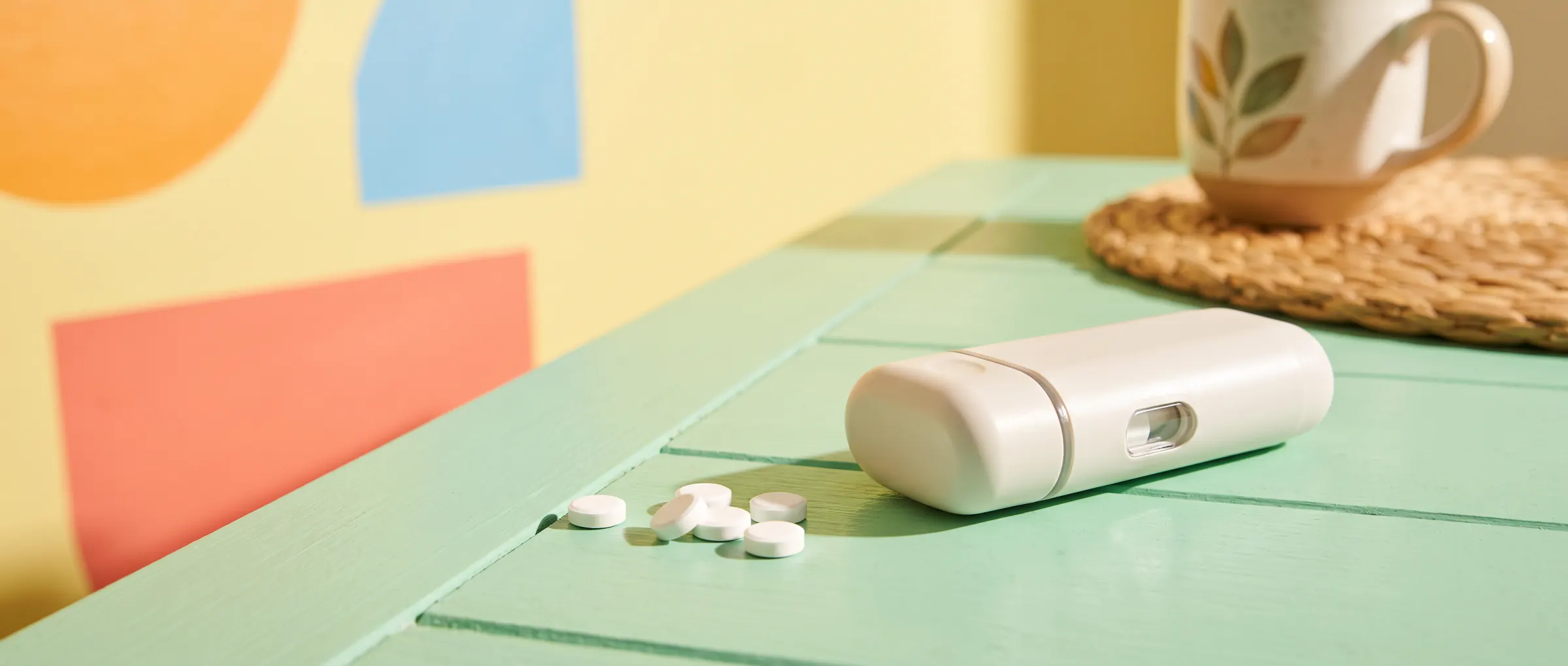 A few white tablets beside an injection pen on a sunny table